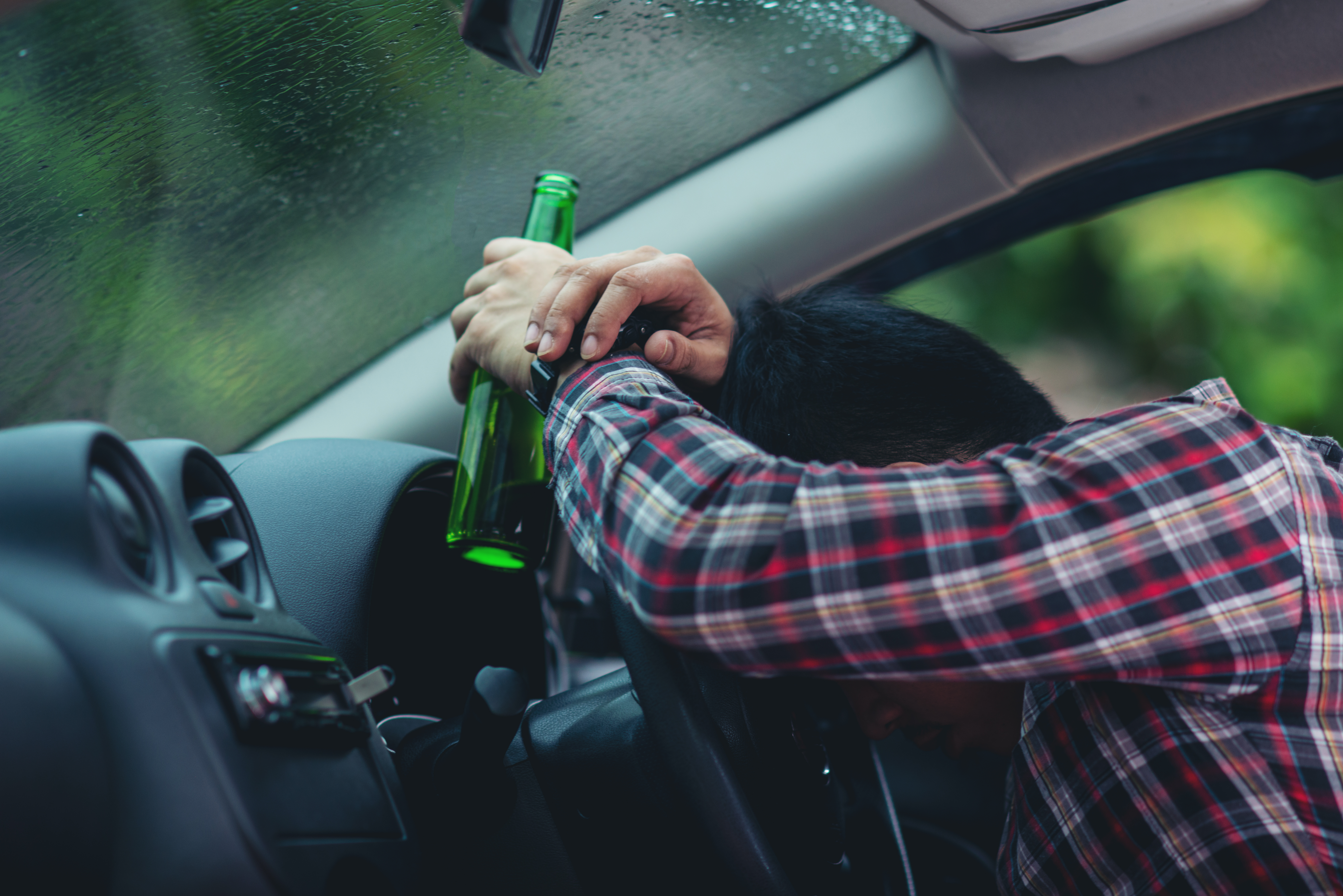 Asian Man Holds Beer Bottle While Is Driving Car